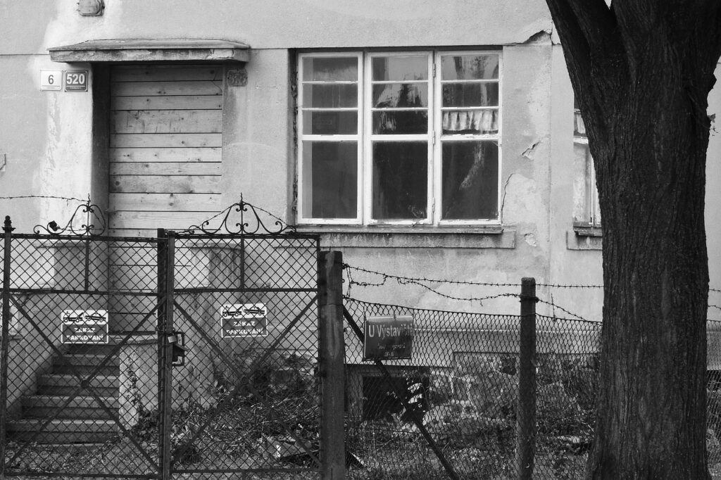 maison abandonnée et défraichie, dont l'acces à été interdit avec un grillage, des barbelés et des pancartes. Photo en noir et blanc